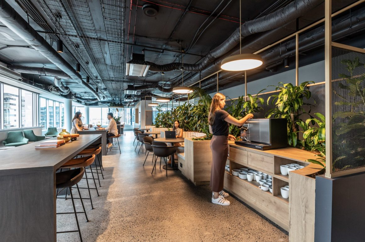 Breakout area with a coffee station, planters and communal tables in a serviced office at 154 Melbourne Street, Brisbane
